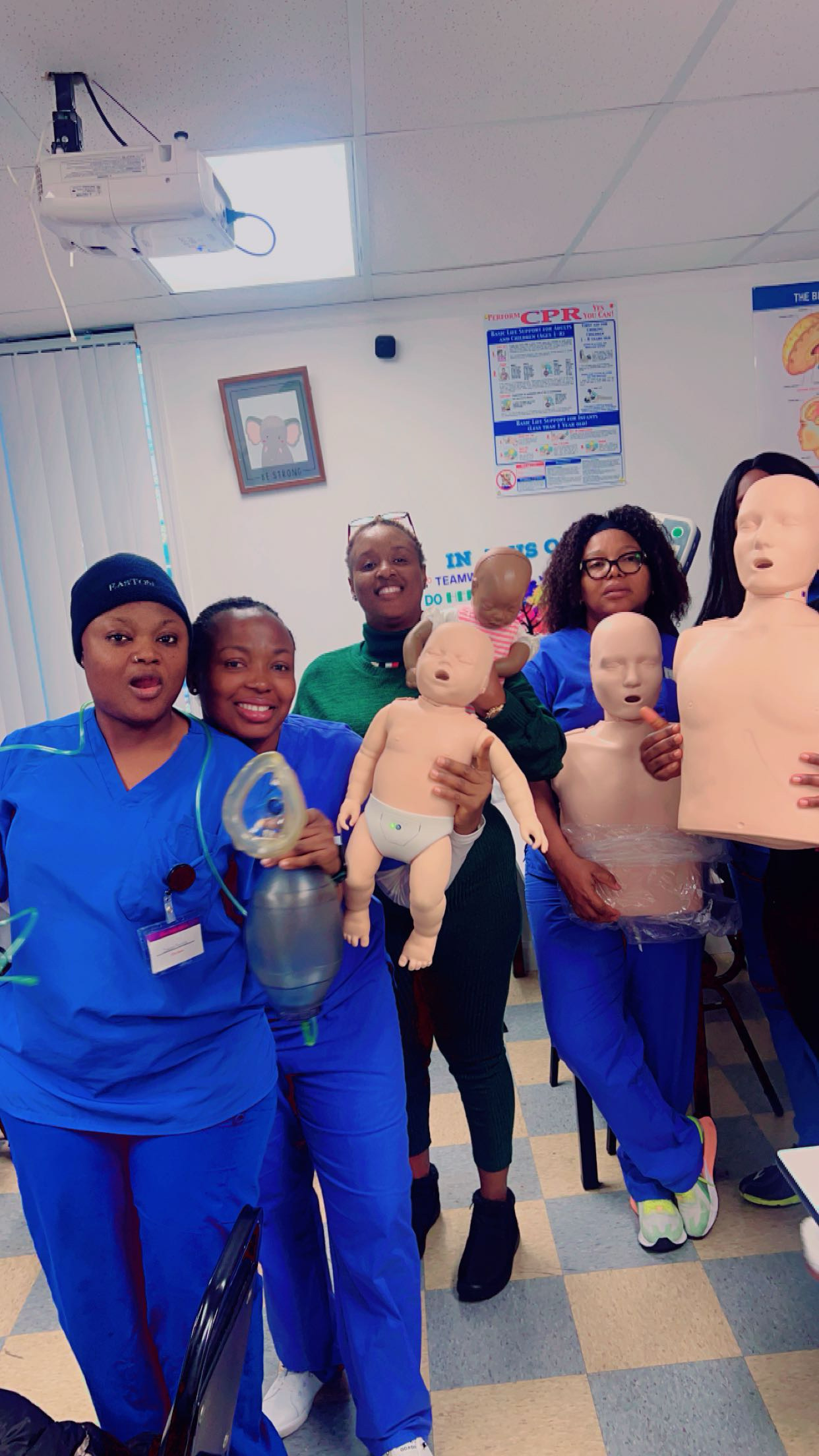 Allure students holding CPR training mannequins in the classroom